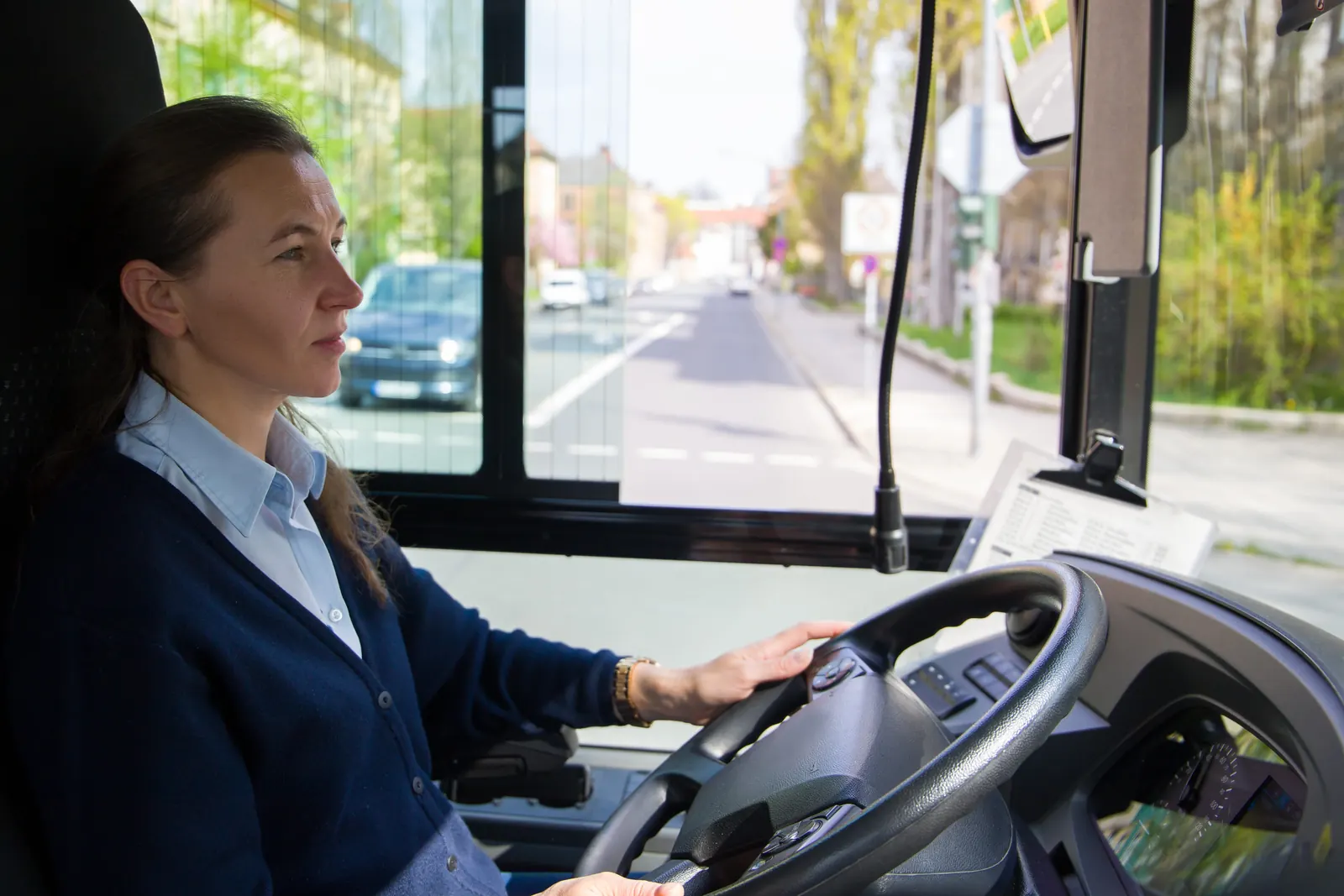 Bussjåfør ved rattet med en bygate foran bussen