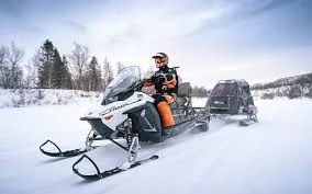 Snøscooterfører trekker en lasteslede over et snødekt område
