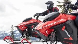 Snøscooterfører med hjelm og heldekkende kjøreutstyr på en rød snøscooter