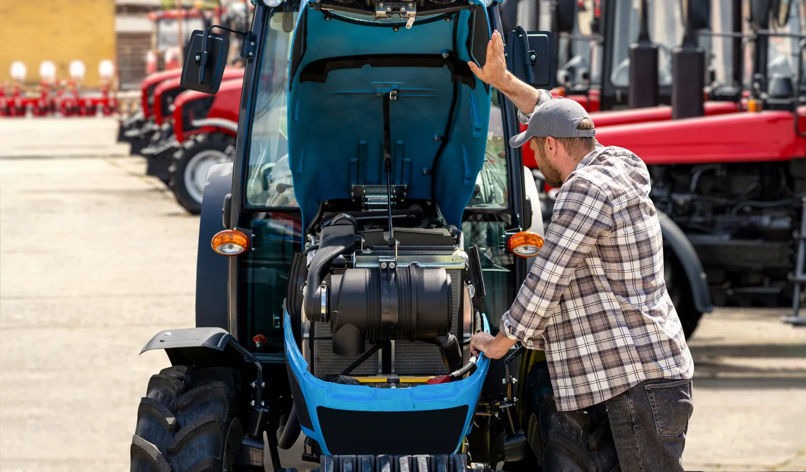 Person undersøker motorrommet på en blå traktor