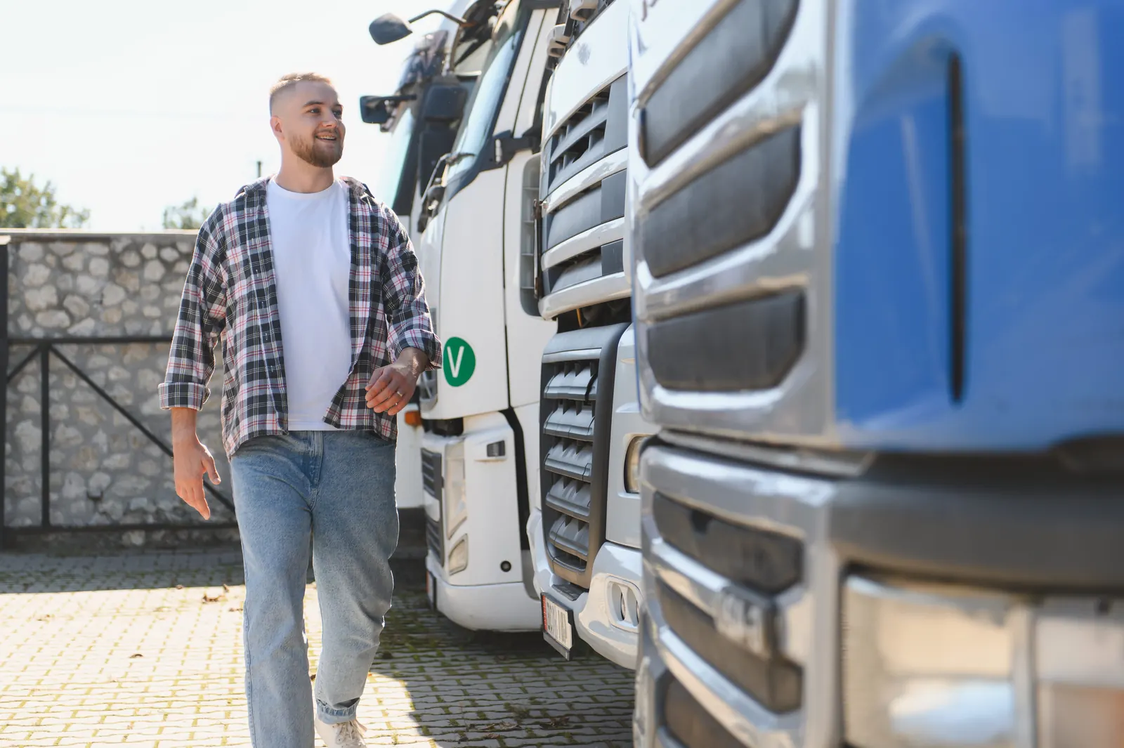 Lastebilsjåfør går mellom parkerte lastebiler før kjøring